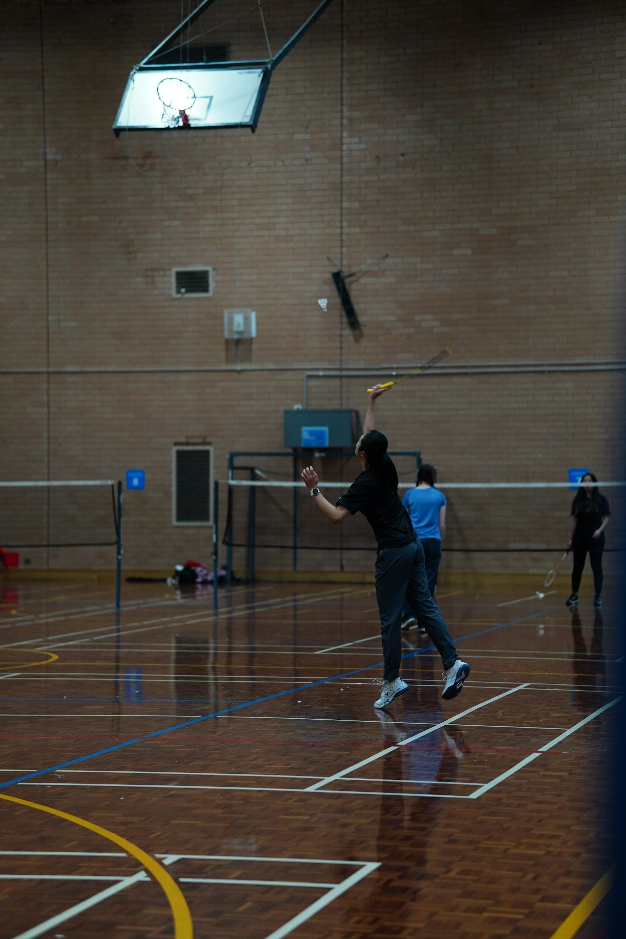 Player leaping for a high serve on an indoor court