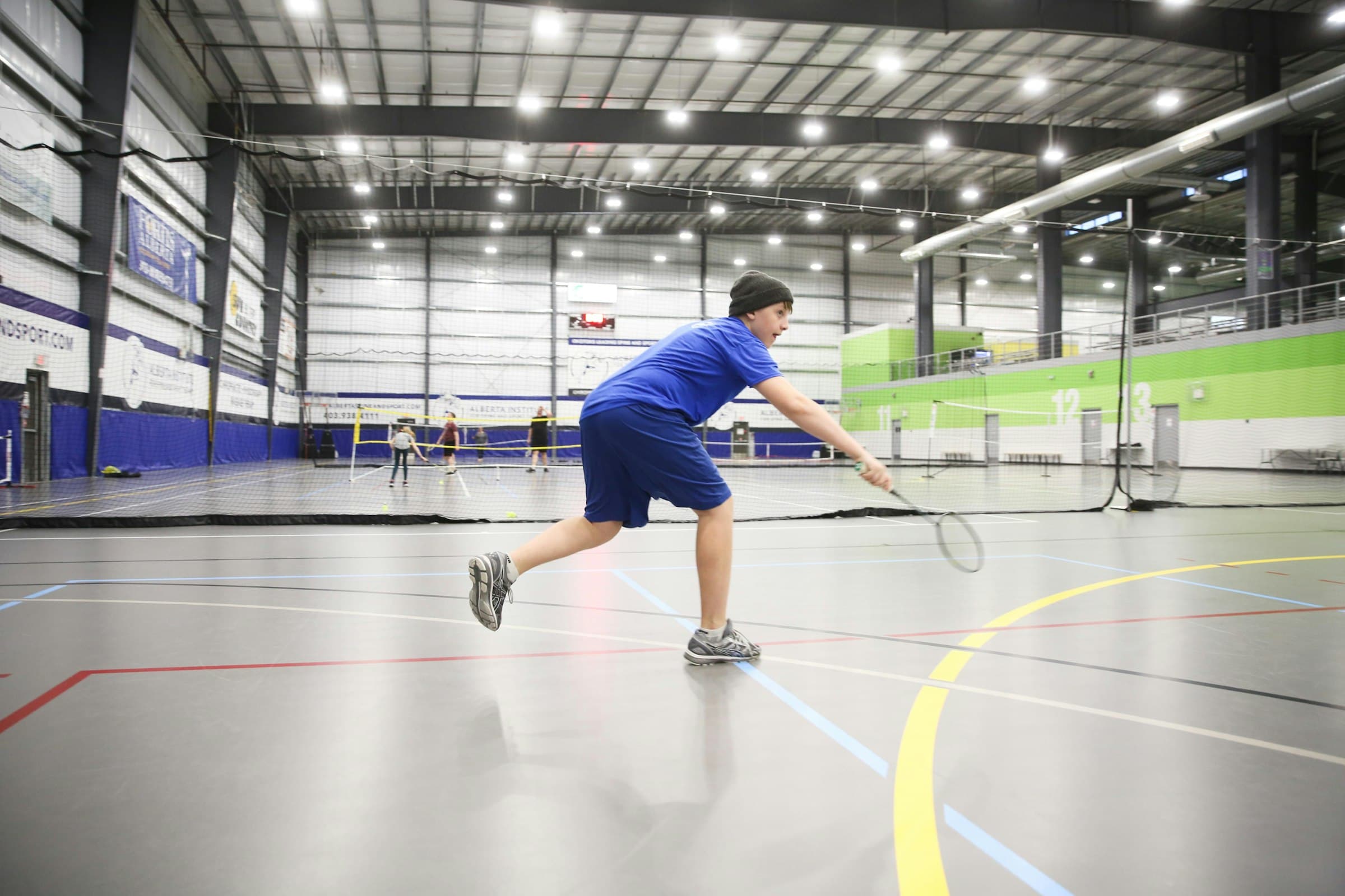 Players training on a badminton court inside a gymnasium