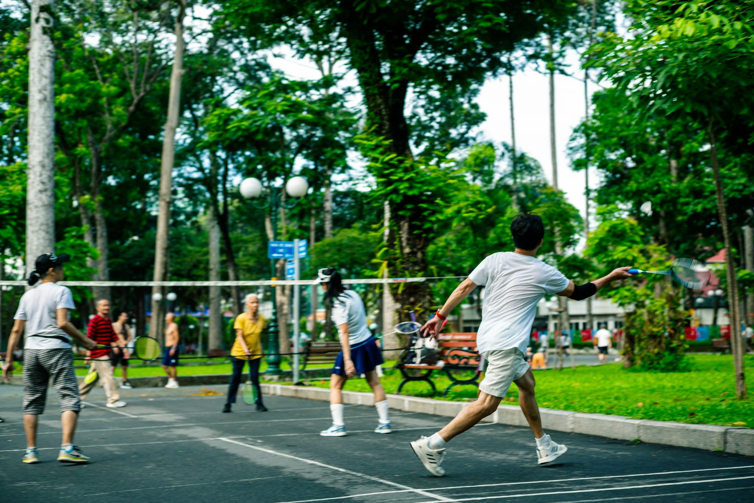 A group playing badminton together outdoors in a park